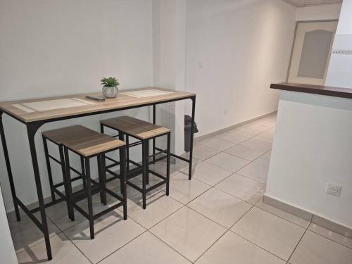 a kitchen with a table and stools in a room at La Bell'appart Ibis rouge in Sinnamary