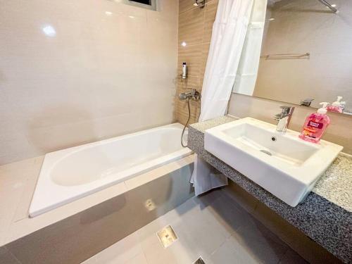 ein weißes Badezimmer mit einem Waschbecken und einer Badewanne in der Unterkunft A2J BGC Luxury Uptown 2BR Balcony Suite Near Malls in Manila