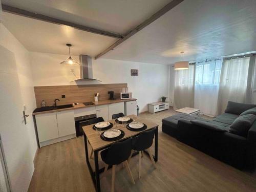 een woonkamer met een bank en een tafel met stoelen bij Appartement proche centre ville in Castres