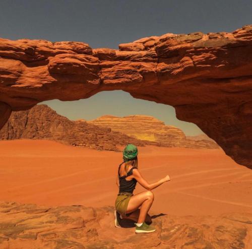 a woman sitting on a rock in the desert at Wadi Rum Meteor camp in Wadi Rum