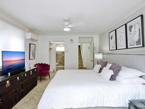 a white bedroom with a large bed and a tv at ZenBreak KingsGate #1 in Saint Peter
