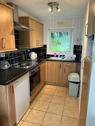 a kitchen with wooden cabinets and a sink and a window at Cosy Chalet for Snowdonia in Caernarfon