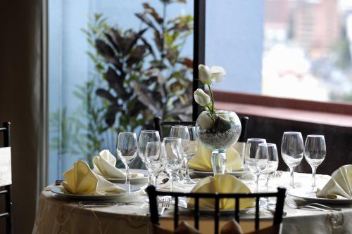 a table with wine glasses and a vase with white flowers at Wyndham Garden Quito in Quito