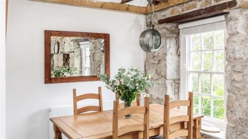 a dining room with a wooden table and a mirror at Boatsman's Cottage- sleeps 4- Garage- Mousehole in Mousehole