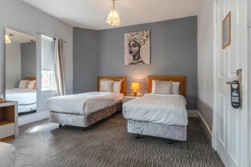 a hotel room with two beds and a mirror at Plough Hotel in Northampton
