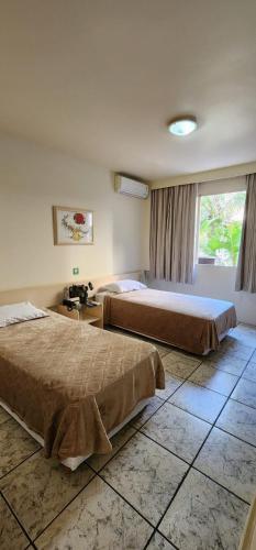 a hotel room with two beds and a window at GoldMen Business Londrina in Londrina