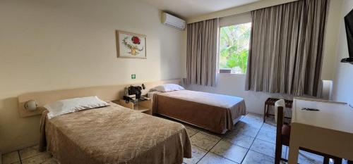 a hotel room with two beds and a window at GoldMen Business Londrina in Londrina
