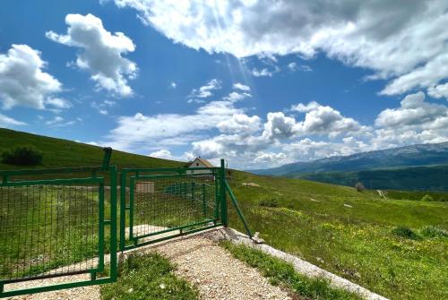 a green gate on a hill with a field at Guest House Highland in Pluzine