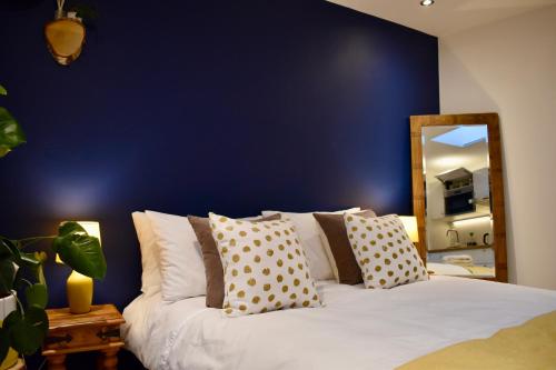 Un dormitorio con una pared azul y una cama con almohadas en Stylish centrally-located studio with parking en Croydon