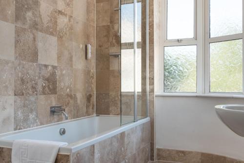 La salle de bains est pourvue d'une baignoire, d'un lavabo et d'une fenêtre. dans l'établissement Plough Hotel, à Northampton