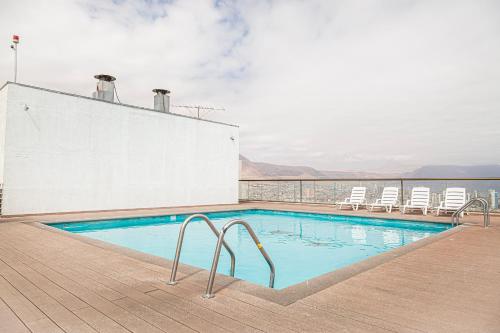a swimming pool on top of a building with chairs at DEPTO SUITE CENTRO I in Iquique