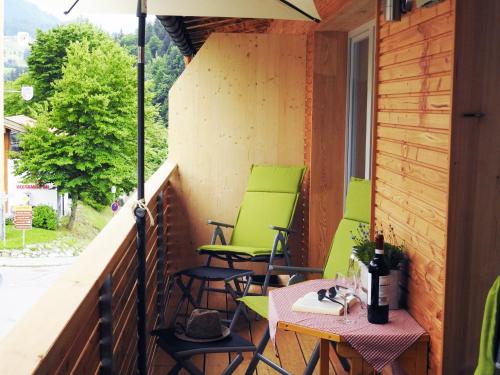 a balcony with green chairs and a table with a bottle of wine at Leos Alpenblume inklusive Sommer Bergbahnticket in Oberstdorf
