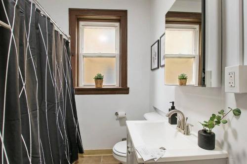 a bathroom with a sink and a toilet and two windows at Warm & Inviting 2BR Apartment - Fullerton 1B in Chicago