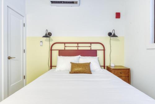 a bedroom with a large white bed with a gold pillow at Sosuite at West Lofts - West Philadelphia in Philadelphia