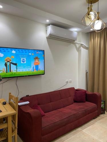 a living room with a red couch and a flat screen tv at Grand Hills in Al Ḩammām
