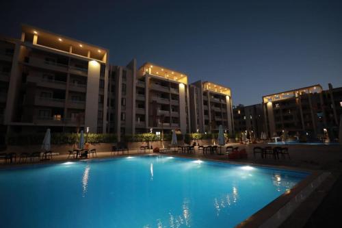 a large swimming pool in front of buildings at night at Grand Hills in Al Ḩammām