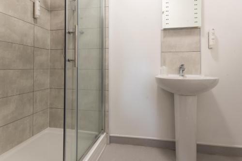 a bathroom with a glass shower and a sink at Plough Hotel in Northampton