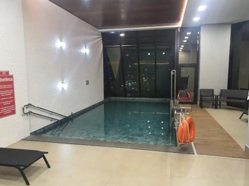 a swimming pool in a building with a pool at Estúdio Alto 22º andar e Elegante no Edifício Vertigo in Campo Grande
