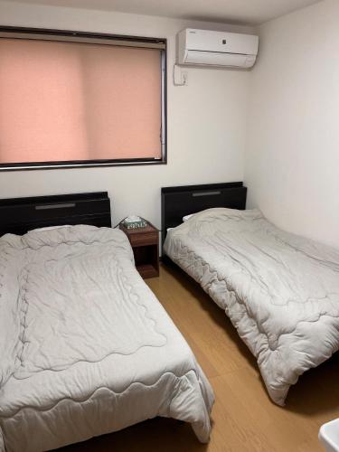 two beds in a room with a window and a bedskirts at Guesthouse Hatenashi - Vacation STAY 43938v in Hongu