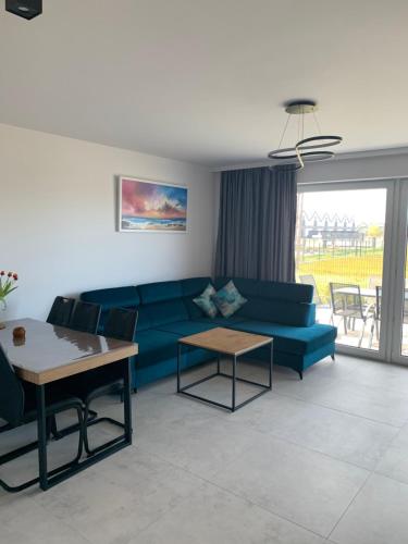 a living room with a blue couch and a table at Apartament Łeba Nowęcin in Nowęcin