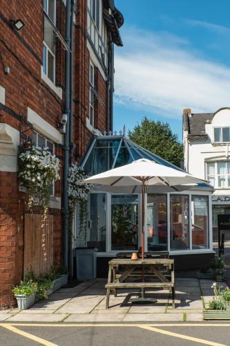 a table with an umbrella in front of a building at Plough Hotel in Northampton
