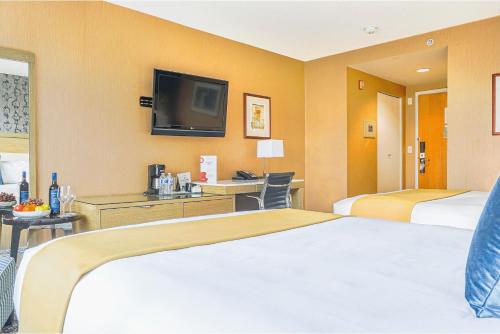 a hotel room with two beds and a flat screen tv at Executive Plaza Hotel & Conference Centre, Metro Vancouver in Coquitlam