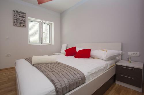 a bedroom with a white bed with red pillows at Lara Apartments in Makarska