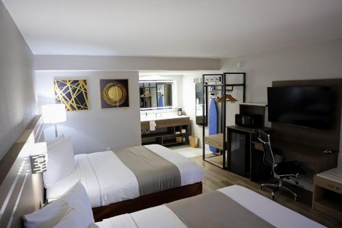 a hotel room with two beds and a flat screen tv at Airport Inn in Nederland
