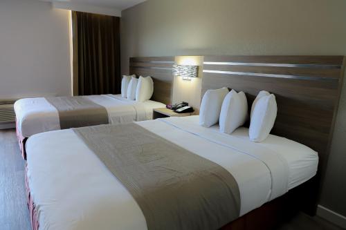 a hotel room with two beds with white pillows at Airport Inn in Nederland