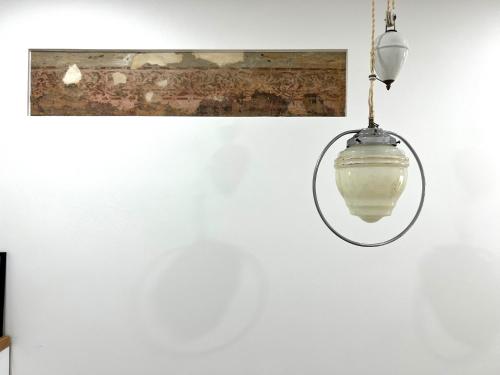 un dispositif lumineux suspendu sur un mur blanc dans l'établissement Cozy studio in Sv Stepono g., à Vilnius