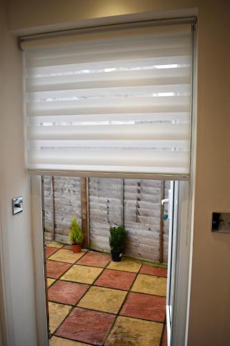a sliding door with a blind over a room with plants at Stylish centrally-located studio with parking in Croydon