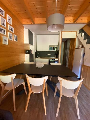 une salle à manger avec une table et des chaises noires dans l'établissement Appartement duplex 6 couchages 2sdb Parking Ménage inclus, à Valmorel