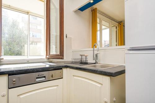 uma cozinha com um lavatório e uma grande janela em Cocon chaleureux, 2 chambres, wifi avec fibre em Grenoble