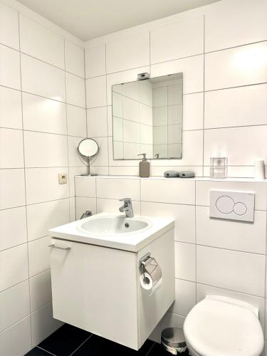 a white bathroom with a sink and a toilet at Heart of Grand Place Beautiful Studio in Brussels