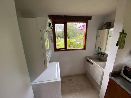 uma pequena cozinha com um lavatório e uma janela em Naturaleza y calma. Finca a 30 minutos de Bogotá. em Facatativa