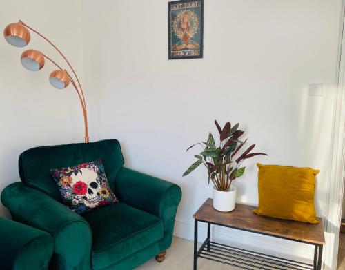 a living room with a green chair and a table at Willow’s Place in Leigh-on-Sea