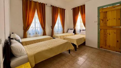 pokój z 3 łóżkami i 2 oknami w obiekcie Shazly Inn w mieście Nazaret
