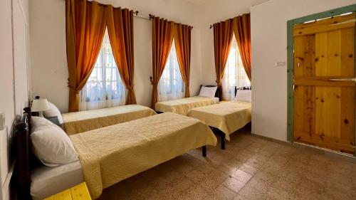 a room with three beds and two windows at Shazly Inn in Nazareth