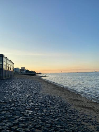 a beach with a building and the ocean at sunset at Willow’s Place in Leigh-on-Sea