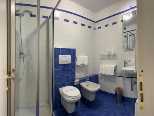 a blue and white bathroom with a toilet and a sink at Aquazzurra Resort & Aparthotel in Cannobio