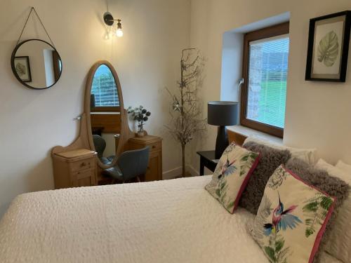 a bedroom with a bed with a mirror and a chair at Milo’s Retreat in Arnside