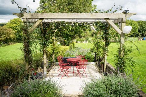 a table and chairs under a pergola in a garden at Kilcatten Lodge in Kilbrittain