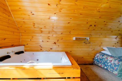 a bath tub in a wooden room with a bed at Chale com hidromassagem Casa Papai Noel in Campos do Jordão
