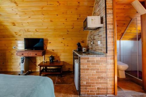 a room with a bathroom with a bed and a kitchen at Chale com hidromassagem Casa Papai Noel in Campos do Jordão