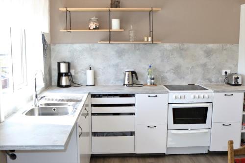 una cucina bianca con lavandino e piano cottura di Grímsstaðir holiday home - Family friendly a Reykholt