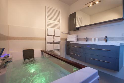 een badkamer met een bad, een wastafel en een spiegel bij Alpine Appart in Bad Hofgastein
