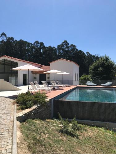 una villa con piscina con sedie e ombrelloni di Casa da Milheira - Agroturismo a Oliveira de Azeméis