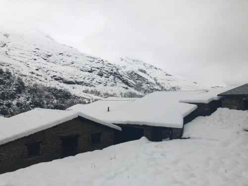 a group of buildings covered in snow at A Barreira -Lar da cima- in Folgoso