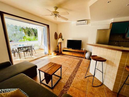 a living room with a couch and a table at Le Palmier Bleu, cocon tropical, plage & piscine in Anse Marcel 