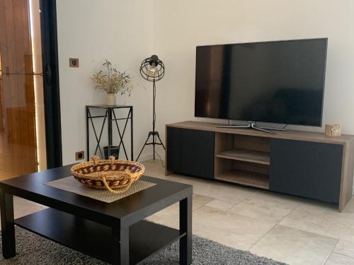 a living room with a large television and a table at Villa La source & SPA in Pont-de-Labeaume